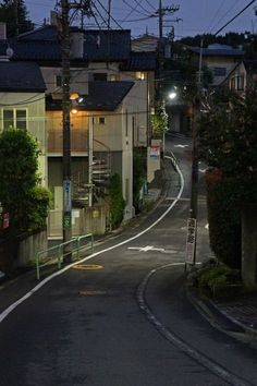 an empty street at night with no cars or people on the road and houses in the background