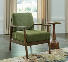 a green chair sitting on top of a rug next to a table with a book