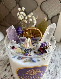 a glass filled with liquid and flowers on top of a table