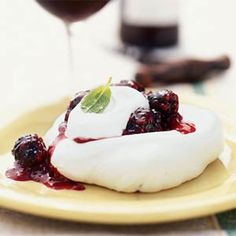 a plate topped with whipped cream and berries next to a glass of wine on a table