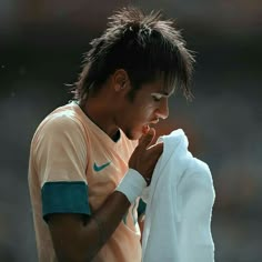 a tennis player wiping his face with a towel