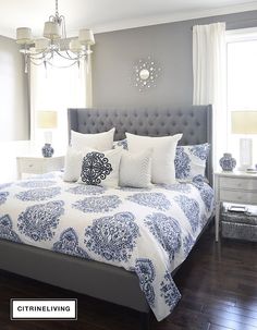 a large bed with blue and white comforter in a bedroom next to a window