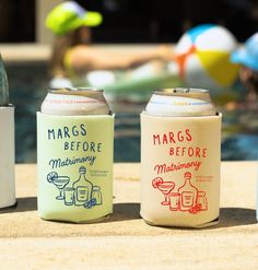 three different types of beer cans sitting next to each other on a table near a swimming pool