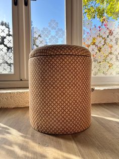 a round ottoman sitting in front of a window