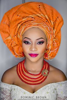 a woman wearing an orange turban and matching necklaces is posing for the camera