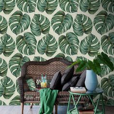 a living room with a wicker couch and wallpaper that has green leaves on it