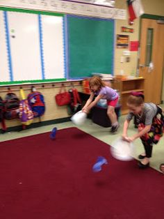 two young children playing with frisbees in a classroom