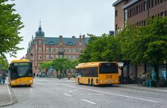 two yellow buses are parked on the side of the road in front of some buildings