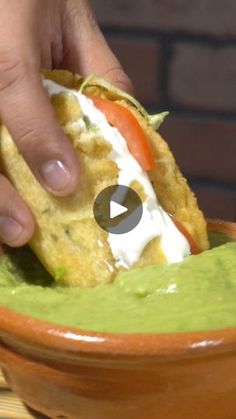 a person dipping guacamole into a bowl