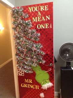 a christmas tree is on display in front of a door that says, you're a mean one