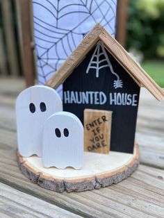 two wooden ghost houses sitting on top of a wooden table next to a black and white house