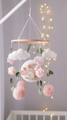 a baby crib mobile with pink flowers and leaves hanging from it's side