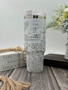 a white and gold travel mug sitting on top of a wooden table next to some books