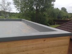 a flat roof on top of a wooden building with trees in the backgroud