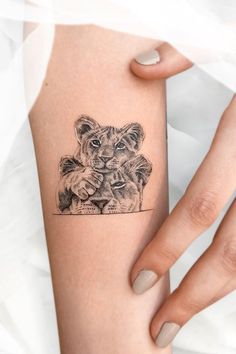 a woman's arm with a small tattoo of two lions on the left side