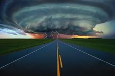 an image of a road that is in the middle of nowhere with storm clouds above it