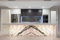 a modern kitchen with marble counter tops and stainless steel appliances, along with an island in the middle