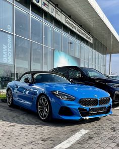 two cars parked in front of a bmw dealership