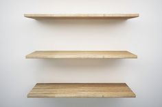 three empty wooden shelves against a white wall