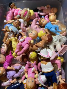 a plastic container filled with lots of toy figurines and toys like barbies