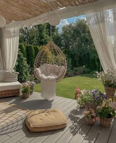 an outdoor area with wicker furniture and flowers on the floor, covered in white drapes