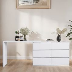 a white dresser with two vases on top of it