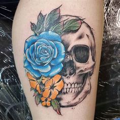 a skull and blue rose tattoo on the thigh