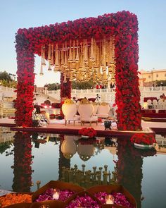 an outdoor ceremony set up with flowers and candles on the water in front of it