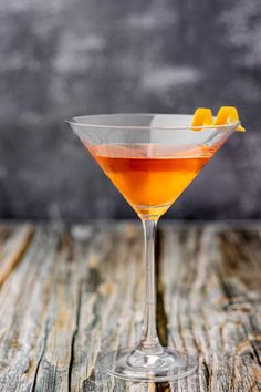 an orange drink in a martini glass on a wooden table