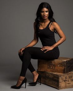 a woman sitting on top of two wooden boxes wearing high heels and black tights