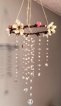 a chandelier with flowers hanging from it's sides and beads on the bottom