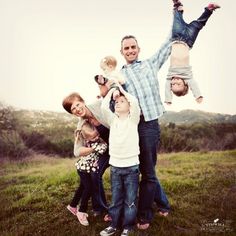 the family is posing for a photo with their two children in front of an open field