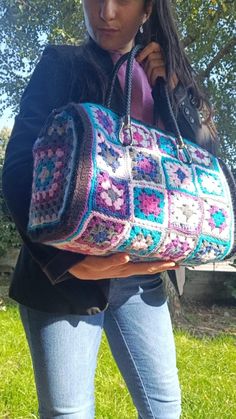 a woman holding a crocheted purse in her hands