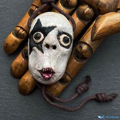 a wooden sculpture with a face on top of it and two hands holding the same object