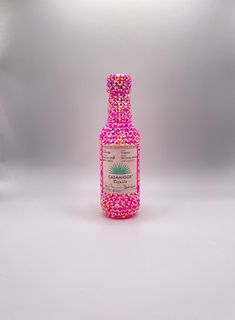 a bottle filled with lots of pink sprinkles on top of a white surface