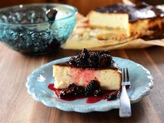 a piece of cheesecake on a plate with berry sauce and a fork next to it