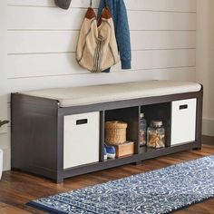 a bench with two storage bins and a coat rack on the wall next to it