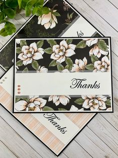 two thank cards with flowers on them sitting next to a plant and some papers that say thanks