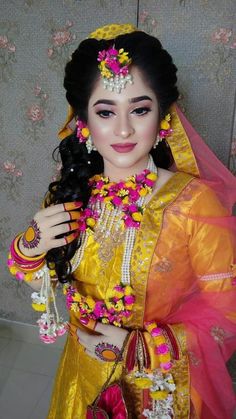 a woman dressed in yellow and pink with flowers on her head, holding a doll