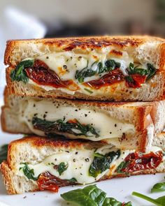 two pieces of bread with cheese and spinach on them sitting on a white plate