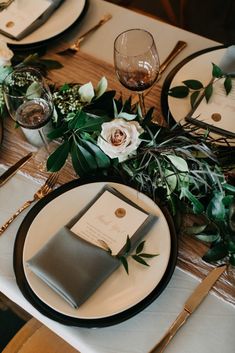 the table is set with place settings, silverware, and greenery for an elegant touch