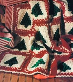 a crocheted christmas tree afghan with red ribbon