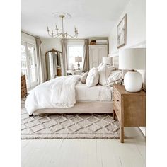 a large white bed sitting in a bedroom on top of a wooden dresser next to a window