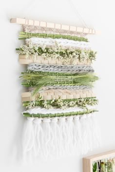 a wall hanging made out of different types of weavings and flowers on a white wall