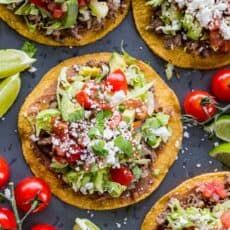 mexican food with tomatoes, lettuce and other toppings on a black surface