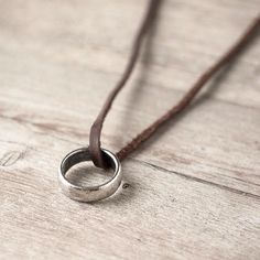 a silver ring on a brown cord with the word love is in it's center