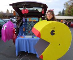 a woman standing in front of a car with an odd shaped object on it's trunk