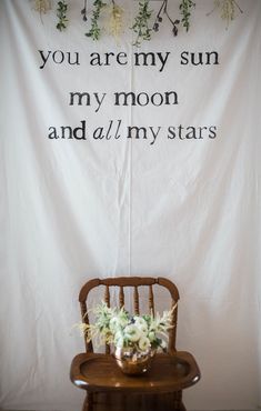 a chair with flowers on it in front of a white banner that says you are my sun, my moon and all my stars