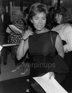 black and white photograph of woman holding papers in her right hand while standing next to other people