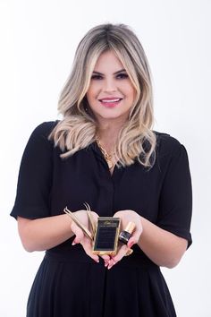 a woman is holding an award in her hands and smiling at the camera while standing against a white background